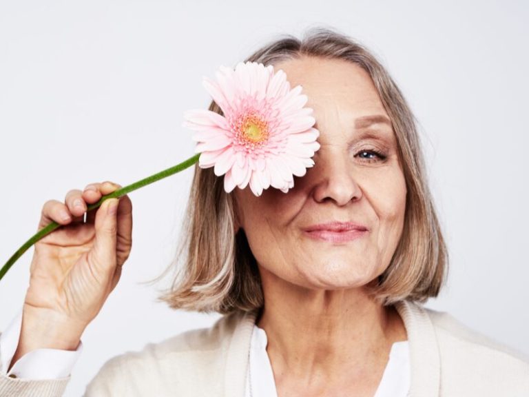 Mulher madura e autoconfiante sorrindo em um ambiente acolhedor, representando o bem-estar na menopausa